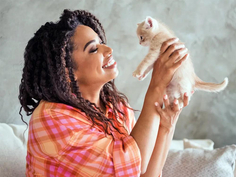woman holding up foster kitten